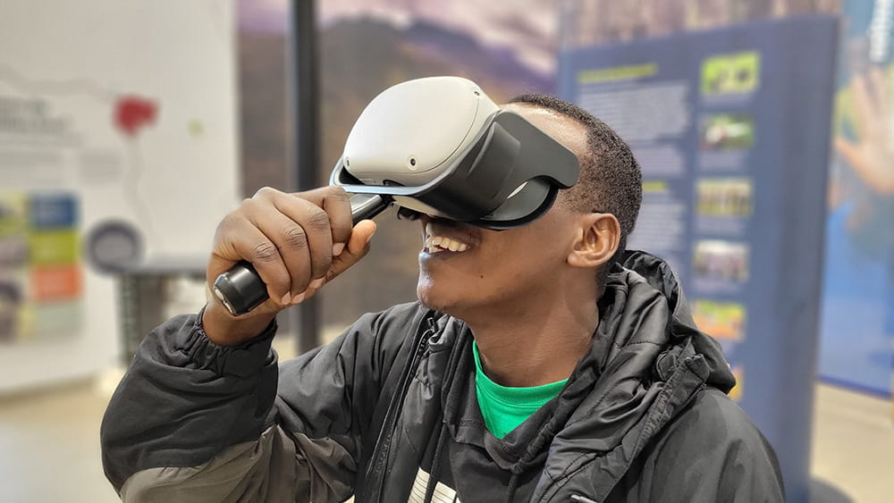 A visitor smiles while engaging with an immersive experience using a custom-designed VR headset and controller.